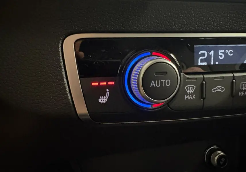 Bouton de réglage automatique de la climatisation avec indication de siège avant chauffant dans un Audi Q2 noir Mythic.
