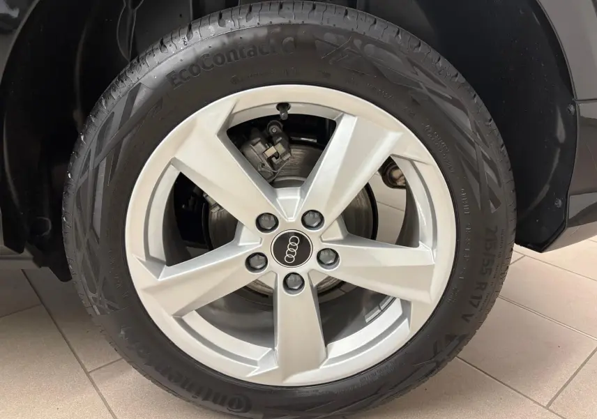 Gros plan sur la roue avant gauche de l’Audi Q2 35 TFSI 150 S Line noire avec jante argentée cinq branches.
