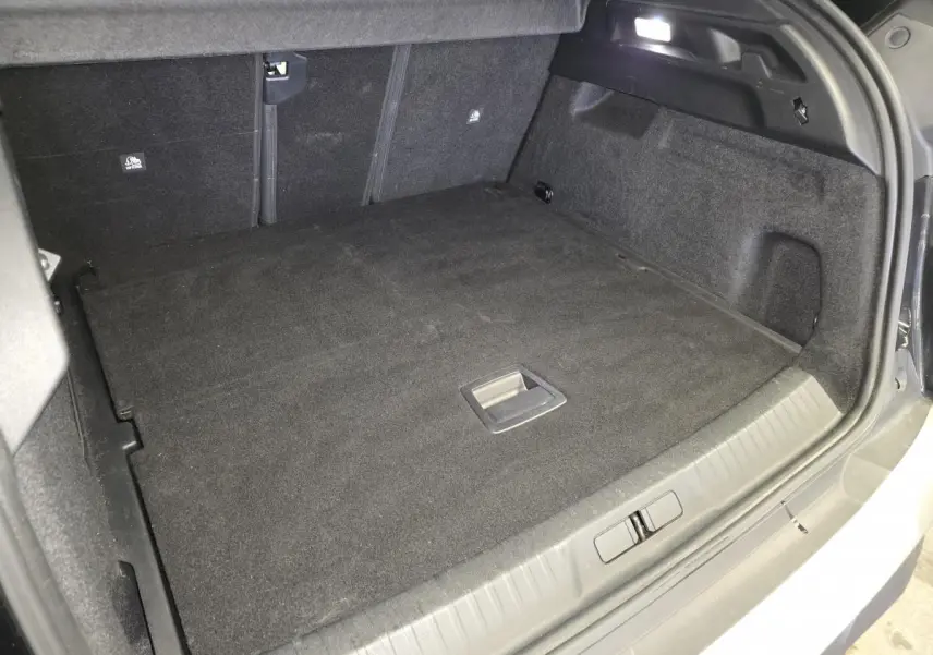 Coffre spacieux et propre du Peugeot 3008 noir, vu de l'arrière avec plancher plat et éclairage LED intégré.