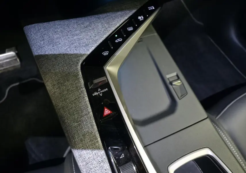 Vue plongeante sur la console centrale du Peugeot 3008 2025, avec tissu gris et commandes noires laquées.