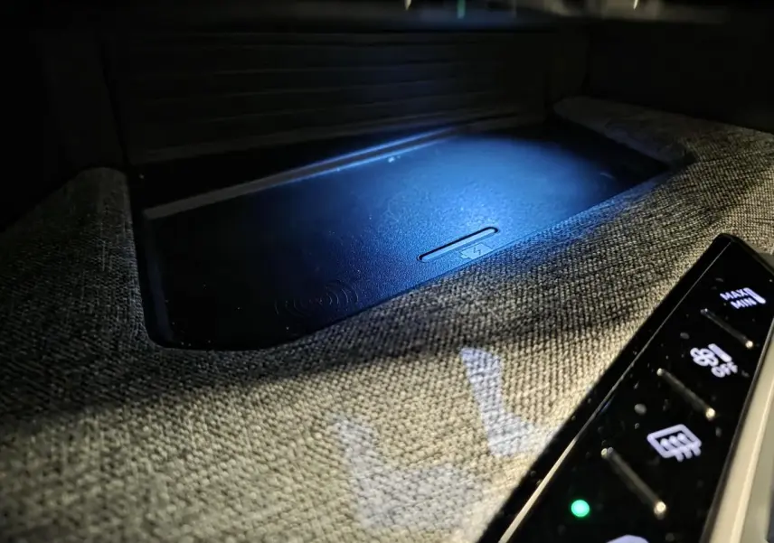 Gros plan sur la console centrale tissu Rimini avec chargeur smartphone sans fil éclairé du Peugeot 3008 noir 2025.