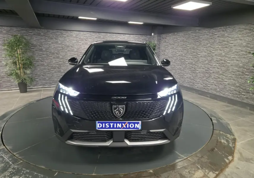 Vue avant d'un Peugeot 3008 noir 2025 avec phares LED griffes et calandre noire laquée en showroom.