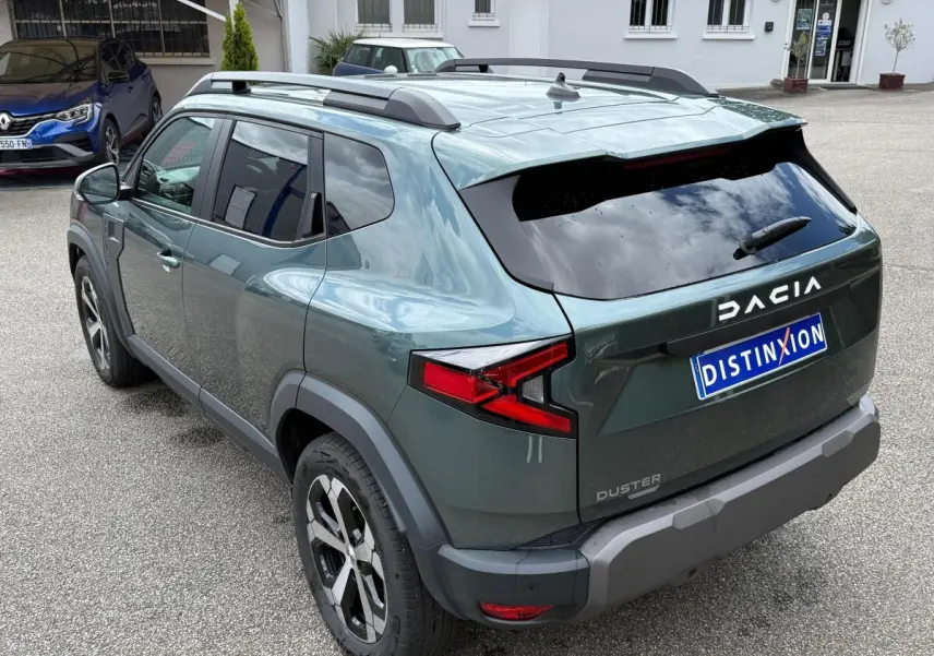 Vue 3/4 arrière droite du Dacia Duster Hybrid 140 Journey vert cèdre avec barres de toit noires et feux arrière LED.