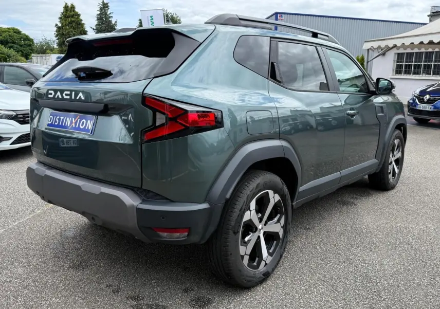 Vue 3/4 arrière droite du Dacia Duster Hybrid 140 Journey vert cèdre avec jantes alliage et barres de toit noires.