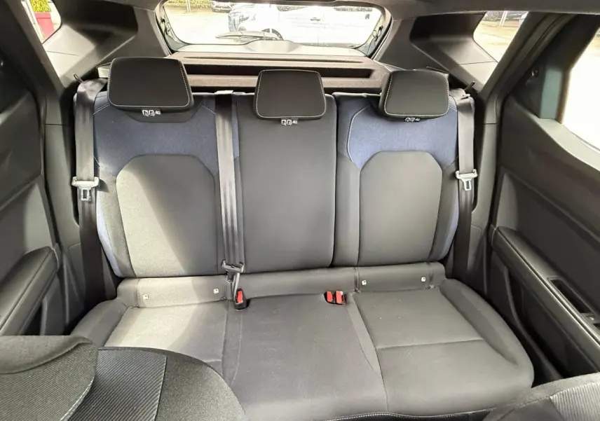 Vue arrière intérieure sur la banquette arrière noire et grise du Dacia Duster Hybrid 140 Journey 2025.