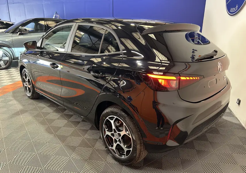 Vue 3/4 arrière droite d'une MG3 Hybrid+ 195 Luxury Pebble Black avec feux arrière allumés et jantes alliage distinctives.