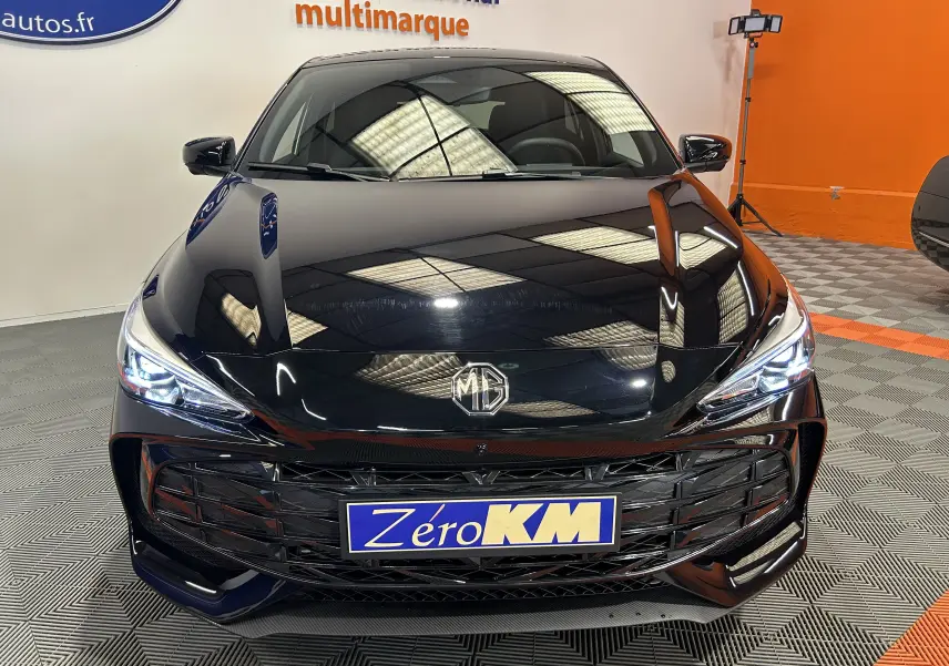 Vue avant d'une MG3 Hybrid+ 195 Luxury Pebble Black avec calandre imposante et phares LED allumés en showroom.