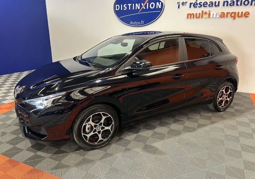 Vue 3/4 avant droite de la MG3 Hybrid+ 195 Luxury noire Pebble Black avec jantes alliage et phares allumés en showroom.