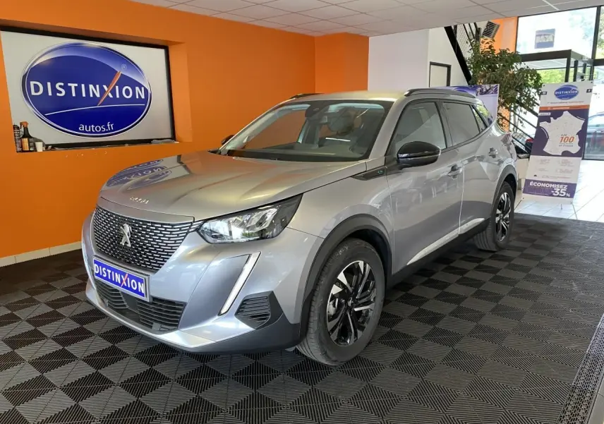 Peugeot 2008 e-136 Allure Pack gris Artense vue 3/4 avant droit en intérieur avec jantes bi-tons et toit noir.