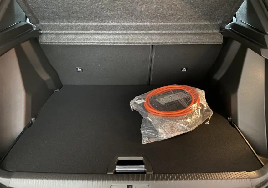 Coffre ouvert d'un Peugeot 2008 e-136 Allure Pack gris Artense avec câble de recharge électrique orange emballé.