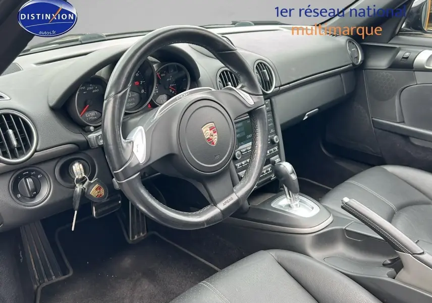 Intérieur noir de la Porsche Boxster 987 vue côté conducteur, volant cuir avec palettes et tableau de bord complet.