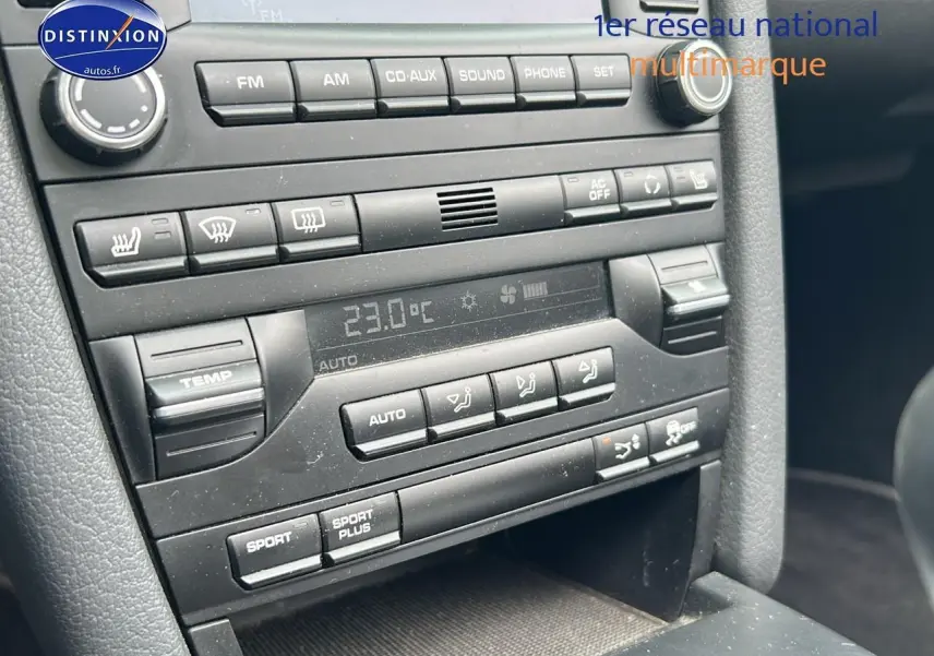 Détail de la console centrale noire d'une Porsche Boxster 987 avec commandes climatisation et audio visibles.