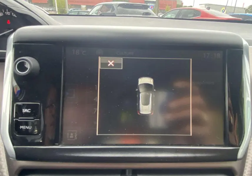 Écran tactile central du tableau de bord du Peugeot 2008 blanc de 2015, affichant la vue de dessus du véhicule en stationnement.