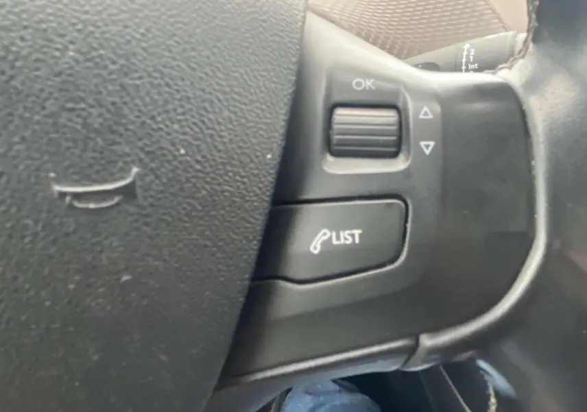 Gros plan sur les commandes au volant du côté gauche d'un Peugeot 2008 blanc, version Allure 2015.