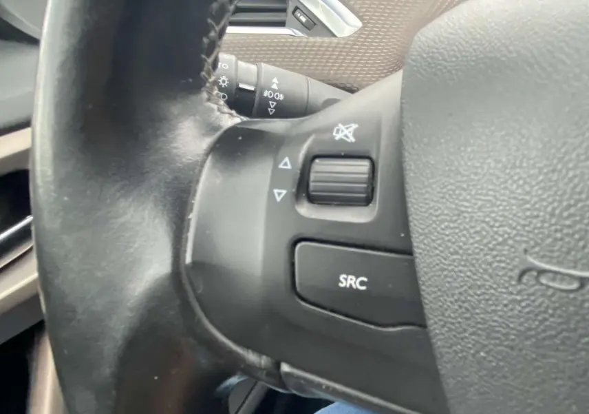 Gros plan sur les commandes au volant du Peugeot 2008 blanc 2015, version essence 1.2i PureTech Allure.