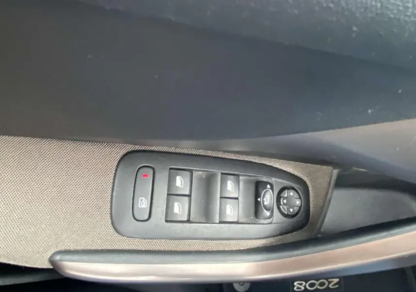 Commande des vitres électriques et rétroviseurs sur la portière côté gauche d'un Peugeot 2008 blanc de 2015.