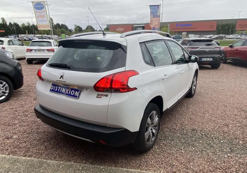 Vue 3/4 arrière droite d'un Peugeot 2008 blanc de 2015 avec logo et feux arrière distinctifs sur parking.