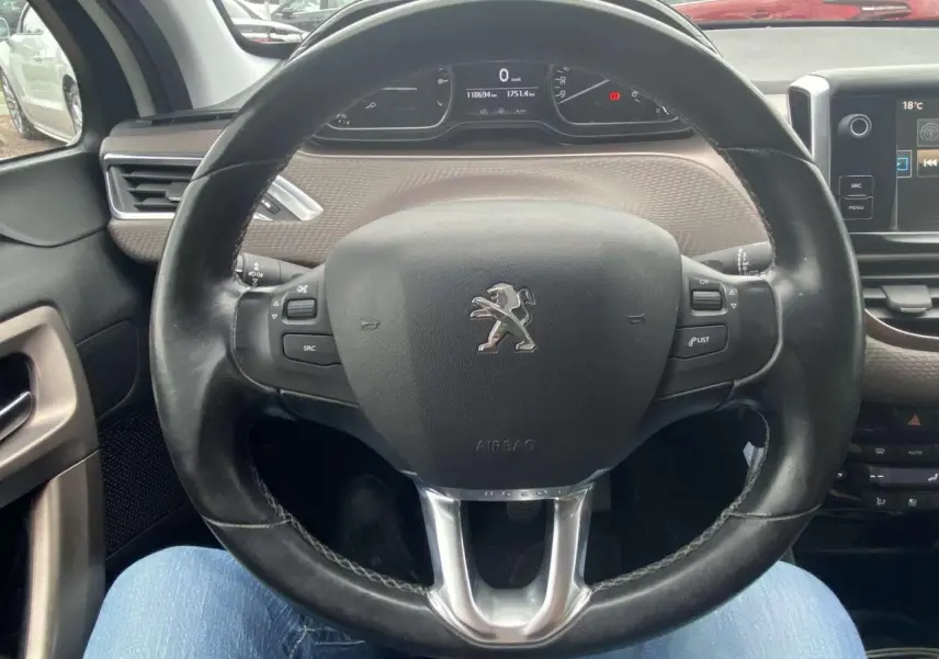 Vue intérieure centrée sur le volant cuir Peugeot 2008 blanc 2015 avec tableau de bord numérique et commandes intégrées.