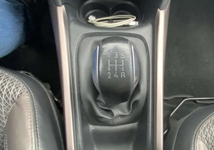 Vue rapprochée du levier de vitesses manuel noir du Peugeot 2008 blanc de 2015, avec console centrale et siège partiel.