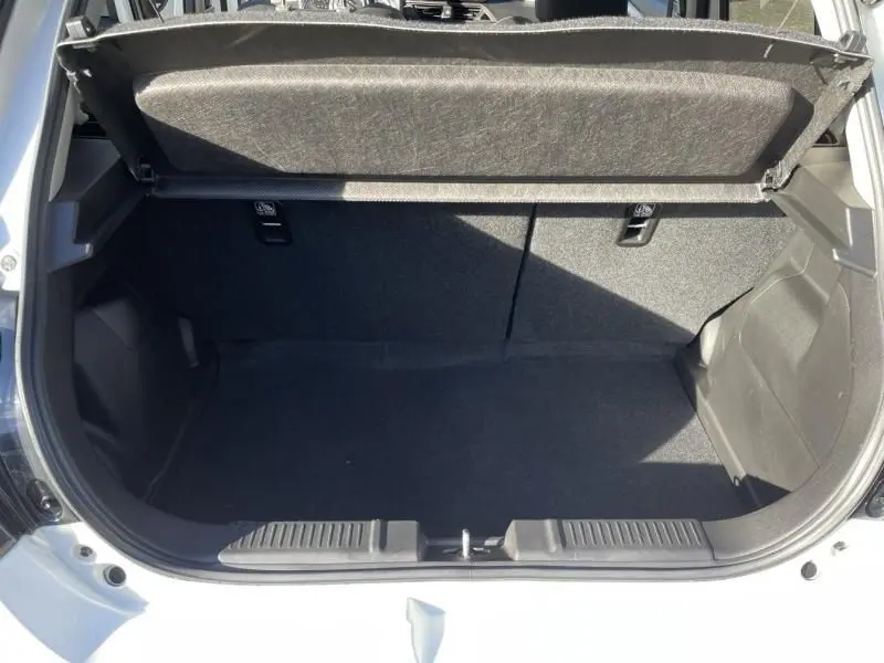 Coffre ouvert vu de l'arrière d'une Suzuki Swift blanche 2025, montrant l'espace de chargement vide et le cache-bagages relevé.