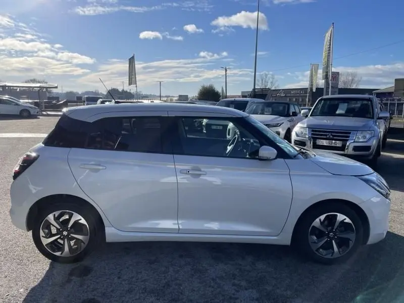 Vue de profil côté gauche d'une Suzuki Swift blanche 2025 avec toit noir et jantes distinctives en alliage.