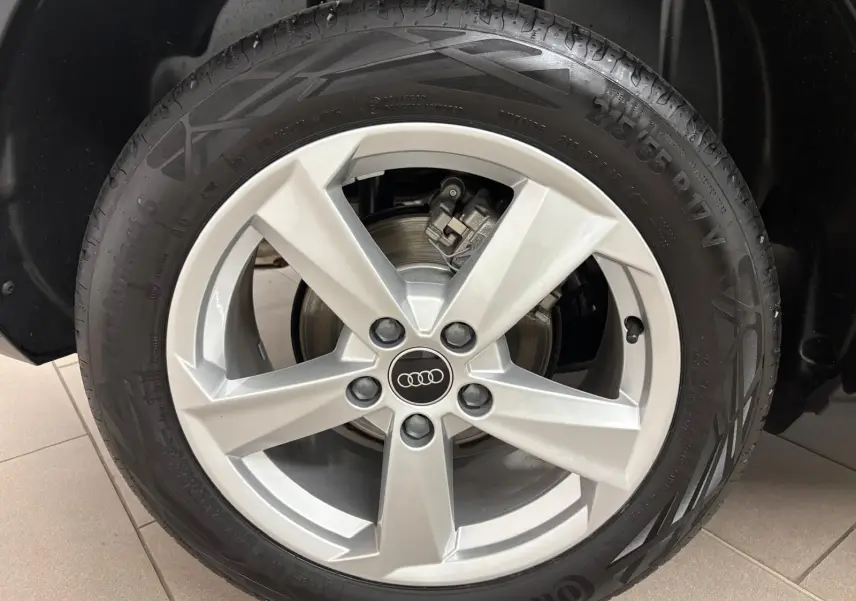 Gros plan sur la roue avant droite de l'Audi Q2 35 TFSI 150 S Line 2026 en Noir Mythic avec jante alliage cinq branches.