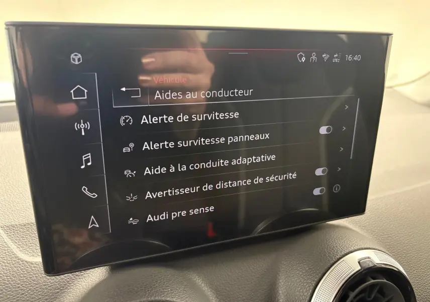 Écran central tactile de l'Audi Q2 35 TFSI S Line 2026 affichant les aides à la conduite, intérieur noir.