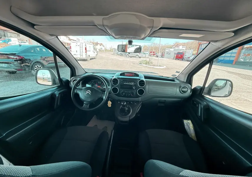 Vue intérieure avant du Citroën Berlingo 2017, montrant le tableau de bord et les sièges en tissu noir.