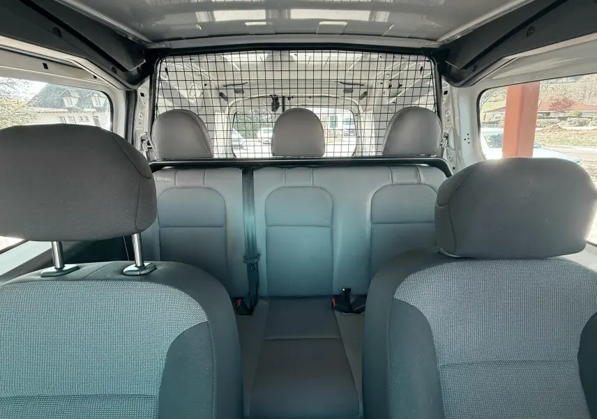 Vue intérieure arrière du Citroën Berlingo 2017, sièges tissu gris et séparation grillagée entre cabine et coffre.