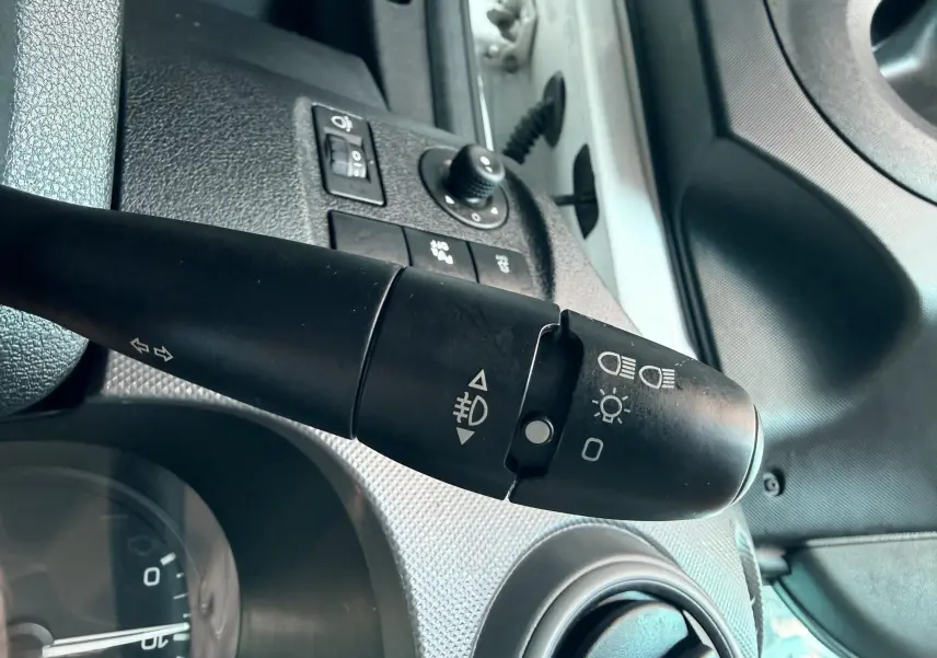 Gros plan sur la manette de clignotants et commandes d’éclairage du tableau de bord d’un Citroën Berlingo blanc, côté conducteur.