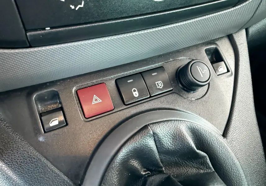 Gros plan sur la console centrale du Citroën Berlingo 1.6 HDI 2017, montrant la commande de vitres, bouton de warning rouge et réglage des rétroviseurs.