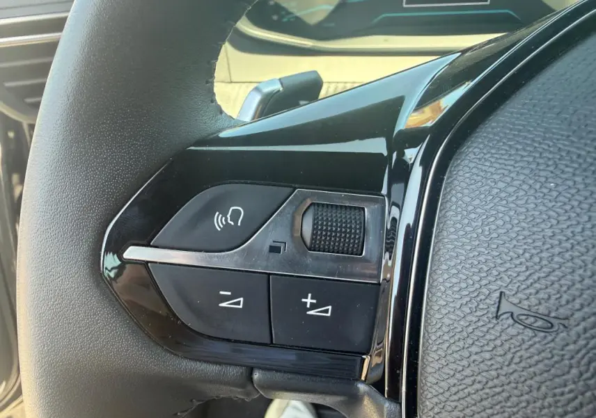 Gros plan sur les commandes vocales et volume au volant du Peugeot 2008 Hybrid 136 e-DCS6 Style noir, intérieur moderne.