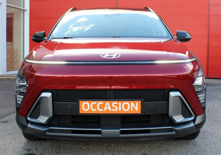 Vue frontale d'un Hyundai Kona 2024 rouge Ultimate Metal avec toit noir et calandre moderne, plaque "OCCASION" orange visible.