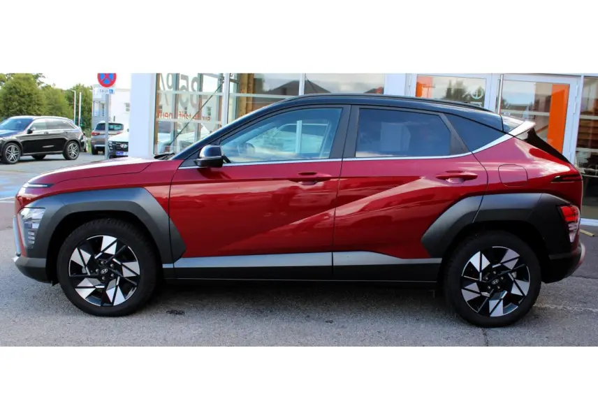 Vue latérale droite du Hyundai Kona 2024 rouge Ultimate Metal avec toit noir et protections d'ailes gris anthracite.