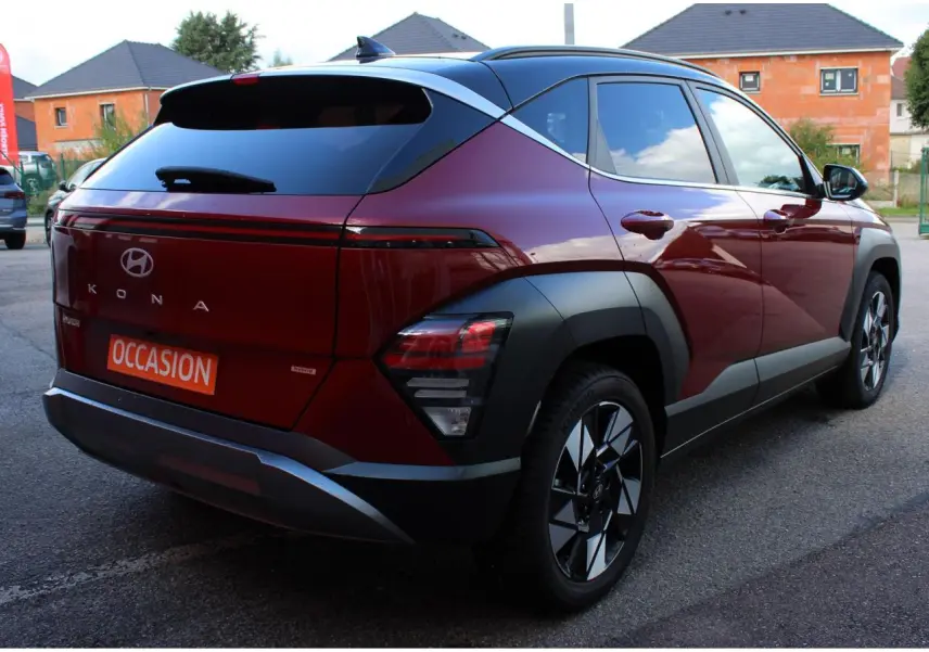Vue 3/4 arrière droite du Hyundai Kona 2024 rouge Ultimate Metal avec toit noir et jantes alliage 17 pouces.