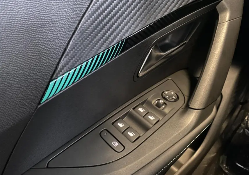Gros plan sur la porte côté gauche du Peugeot 2008 e-136 Allure Pack 2022 avec insert décoratif bleu et commandes de vitres.