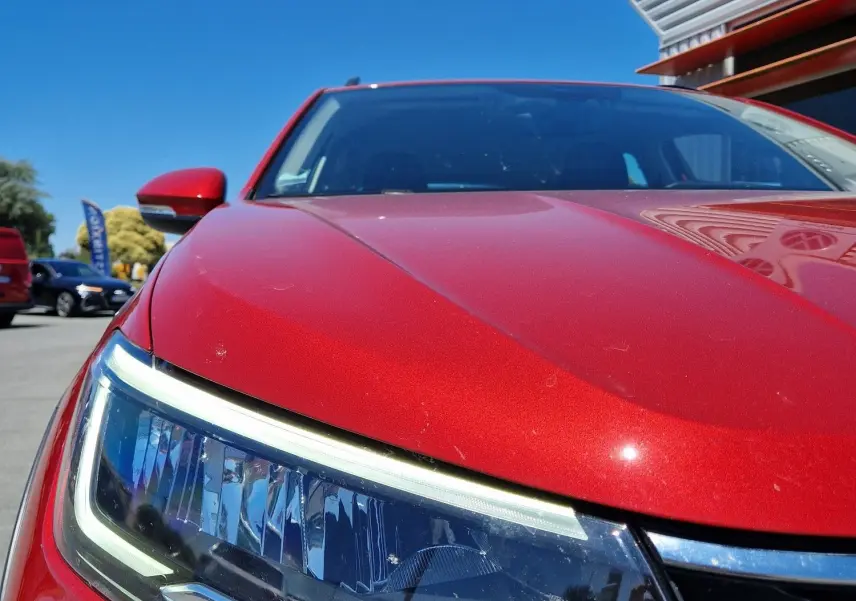 Gros plan sur le phare avant gauche du Volkswagen Taigo rouge roi 2023, soulignant ses lignes modernes et sa calandre chromée.