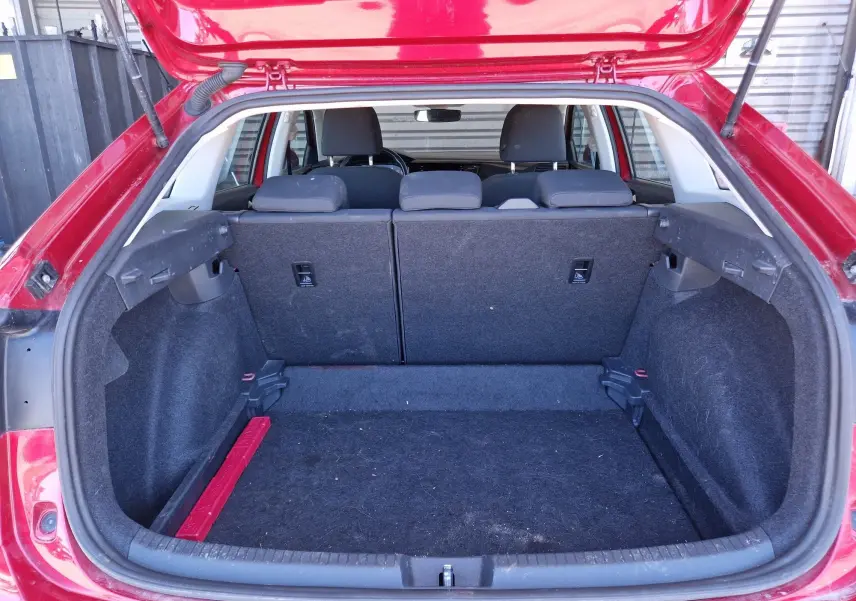 Coffre ouvert vu de l'arrière d'un Volkswagen Taigo rouge roi 2023, montrant l'espace de chargement et les sièges arrière rabattus.