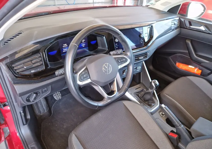 Intérieur du Volkswagen Taigo rouge roi 2023, vue côté conducteur sur le tableau de bord et la boîte manuelle.