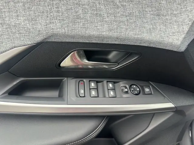 Gros plan sur la commande des vitres et la poignée intérieure côté gauche du PEUGEOT 3008 gris titane 2025.