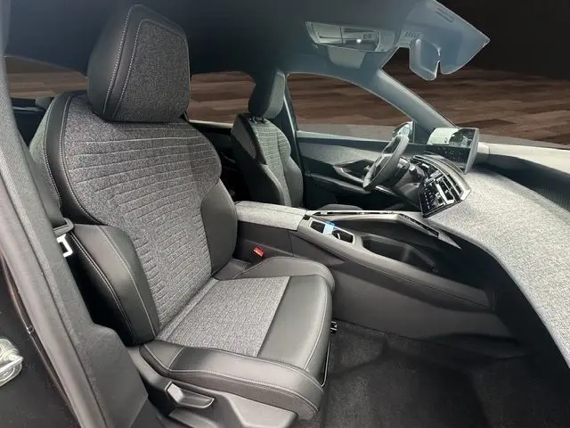 Intérieur avant droit du Peugeot 3008 gris titane 2025, sièges tissu et cuir, tableau de bord moderne avec écran tactile.