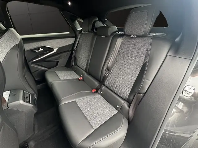 Vue intérieure arrière droite du Peugeot 3008 2025 gris titane, sièges en cuir et tissu gris avec ceinture de sécurité rouge.