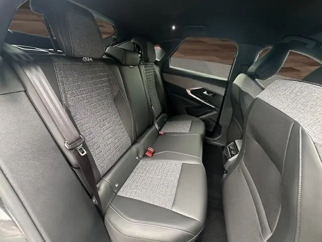 Vue intérieure arrière droite des sièges en tissu et cuir noir du Peugeot 3008 2025 avec vitres surteintées et ceinture de sécurité visible.