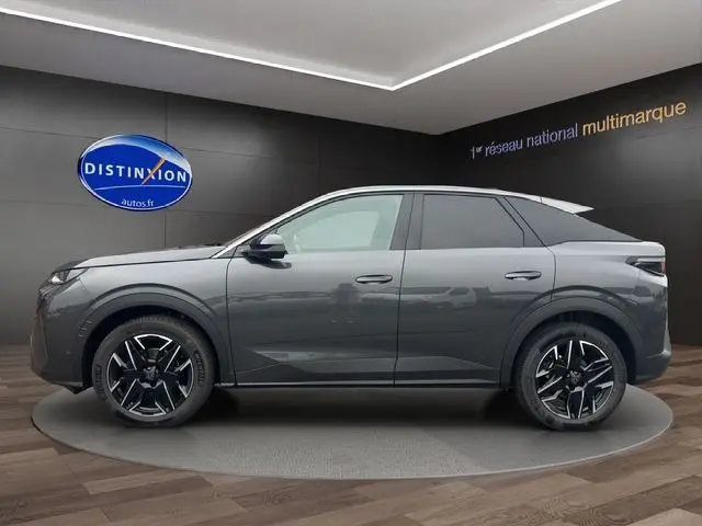 Profil latéral droit du Peugeot 3008 gris titane 2025 avec jantes noires et toit panoramique en showroom