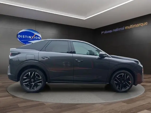 Profil latéral droit d'un Peugeot 3008 gris titane 2025 avec jantes noires et vitres arrière surteintées dans un showroom.