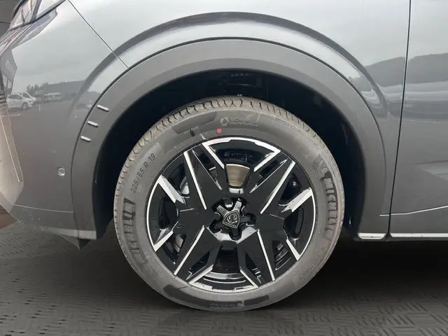 Gros plan sur la roue avant gauche du Peugeot 3008 gris titane, mettant en valeur la jante noire et argentée design.