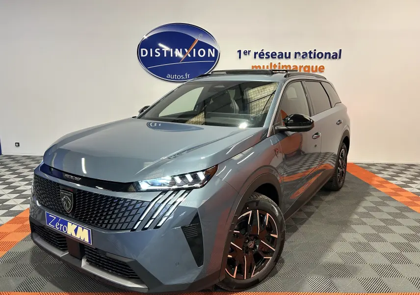 Vue 3/4 avant d’un Peugeot 5008 bleu Ingaro avec jantes noires et toit ouvrant panoramique en intérieur showroom.