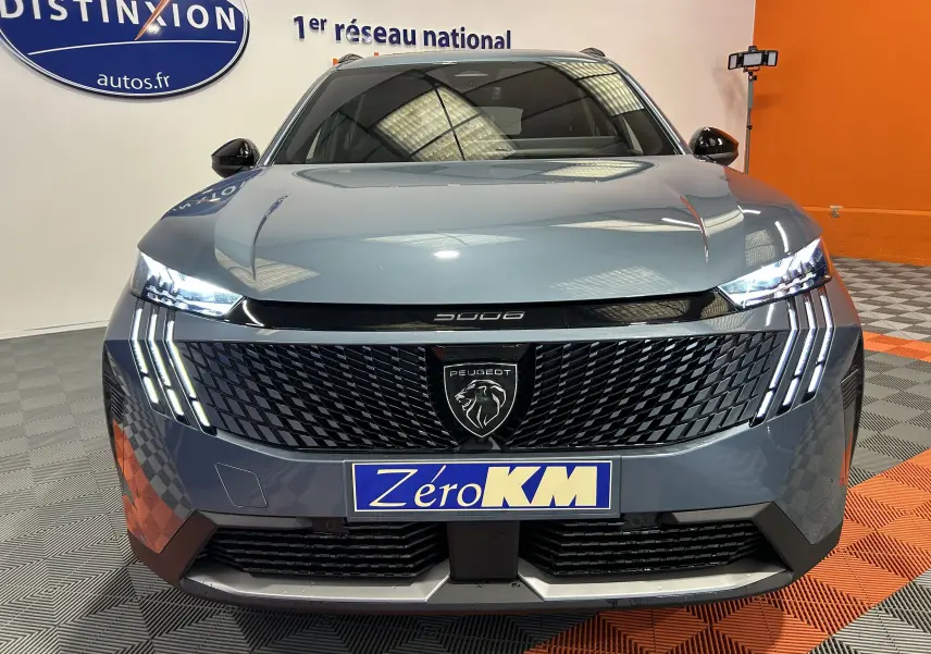 Vue frontale du Peugeot 5008 III Hybrid 145 GT bleu Ingaro avec phares LED allumés et calandre noire texturée.
