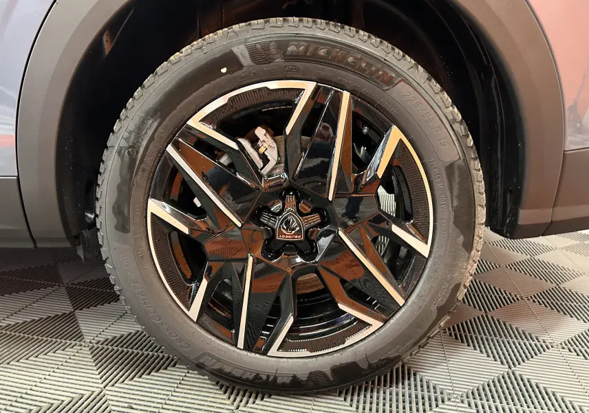 Gros plan sur la jante avant droite noire et argentée du Peugeot 5008 III Hybrid 145 GT Bleu Ingaro.
