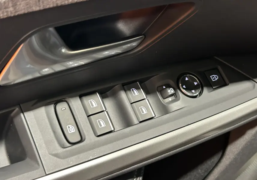 Gros plan sur les commandes des vitres et rétroviseurs côté conducteur du Peugeot 5008 III Hybrid 145 GT, intérieur noir.